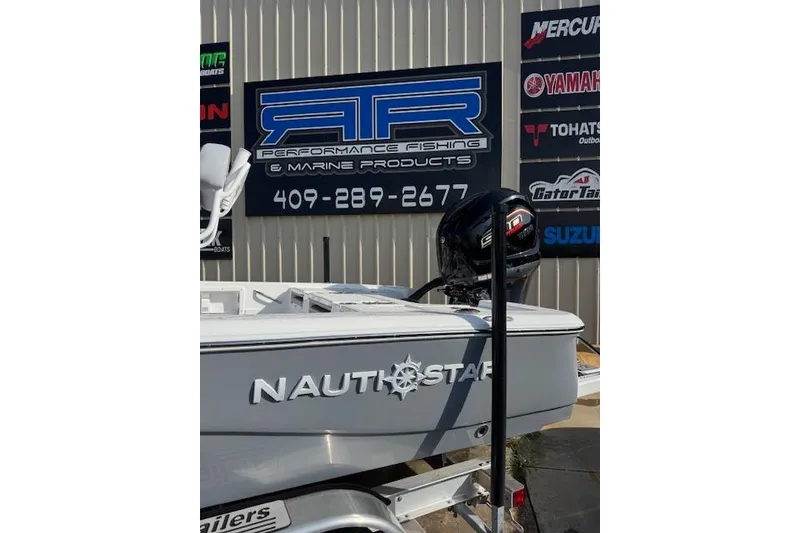 Slide: The Image of 2025 NauticStar 224 Bay boat at marine dealership, featuring outboard motor and signage. - 2