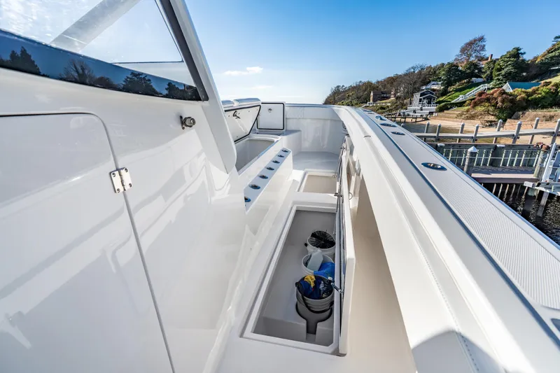 Slide: The Image of 2025 Front Runner 43 Catamaran deck with storage compartments, docked by scenic shoreline. - 27