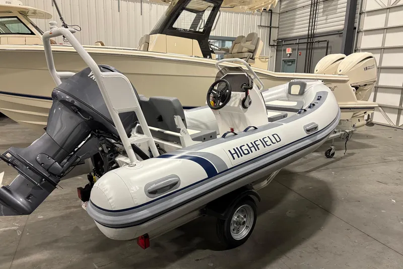Slide: The Image of 2025 Highfield Classic 400 inflatable boat in a showroom, featuring a powerful outboard motor. - 2