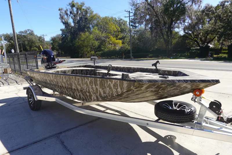 Slide: The Image of 2026 Avid 18 Commander boat on trailer, camo design, parked outdoors. - 13