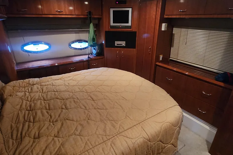 Slide: The Image of Luxurious 2005 Carver 466 Motor Yacht bedroom with wood cabinetry and cozy bedding. - 22