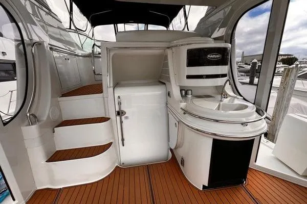 Slide: The Image of 2005 Carver 466 Motor Yacht interior with kitchenette and stairs, featuring sleek design and wood flooring. - 29