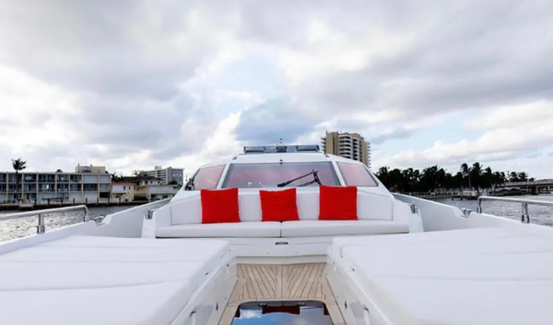 Slide: The Image of Luxurious 2019 Numarine 78 yacht with red cushions, cruising near coastal buildings under a cloudy sky. - 9