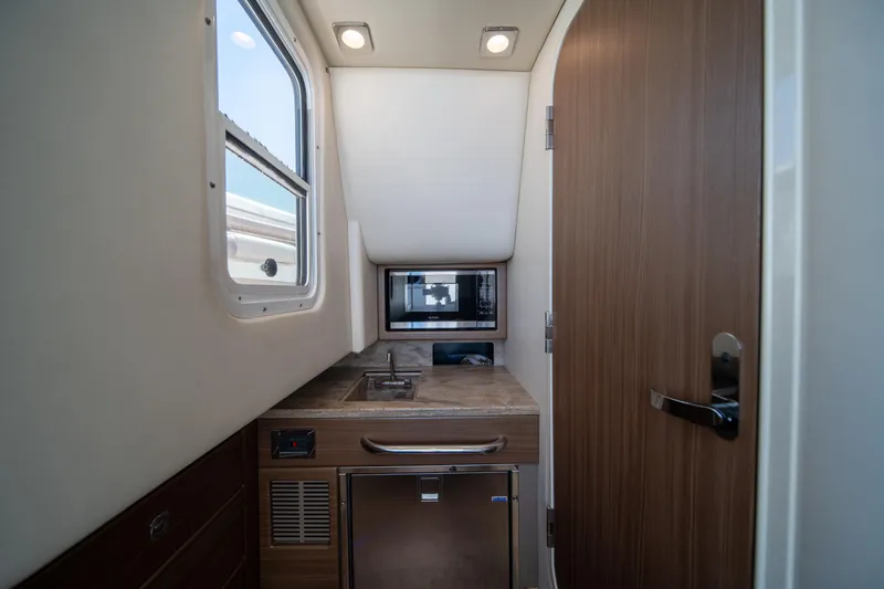 Slide: The Image of Interior of 2018 Formula 350 Crossover Bowrider OB, featuring kitchenette with sink and microwave. - 13