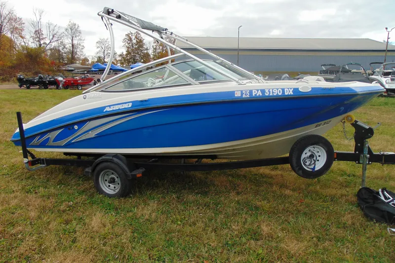 Slide: The Image of 2015 Yamaha AR190 boat in blue on a trailer, parked on grass. - 6