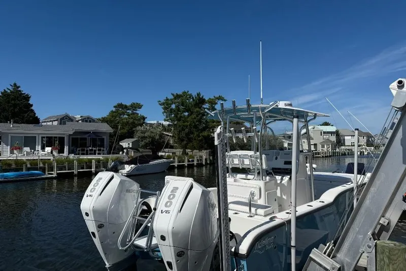 Slide: The Image of 2025 Tideline 235 Hybrid boat docked by waterfront homes under clear blue sky. - 4