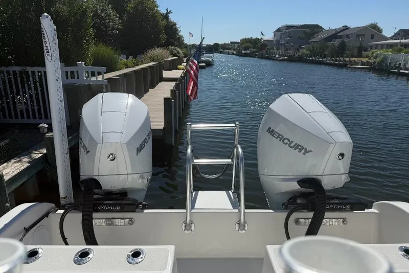 Slide: The Image of 2025 Tideline 235 Hybrid boat with dual Mercury engines docked by a scenic canal. - 5