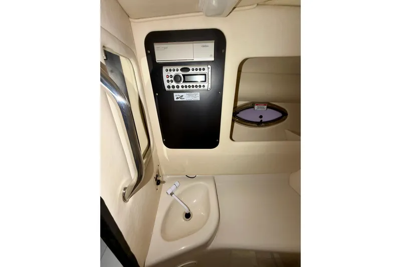 Slide: The Image of 2007 Sea Ray 290 SLX boat interior with white leather seating, docked by a serene lake. - 22