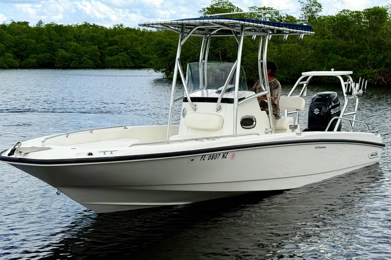 Slide: The Image of 2009 Boston Whaler 230 Dauntless boat on calm water, featuring a sleek design and Suzuki engine. - 2