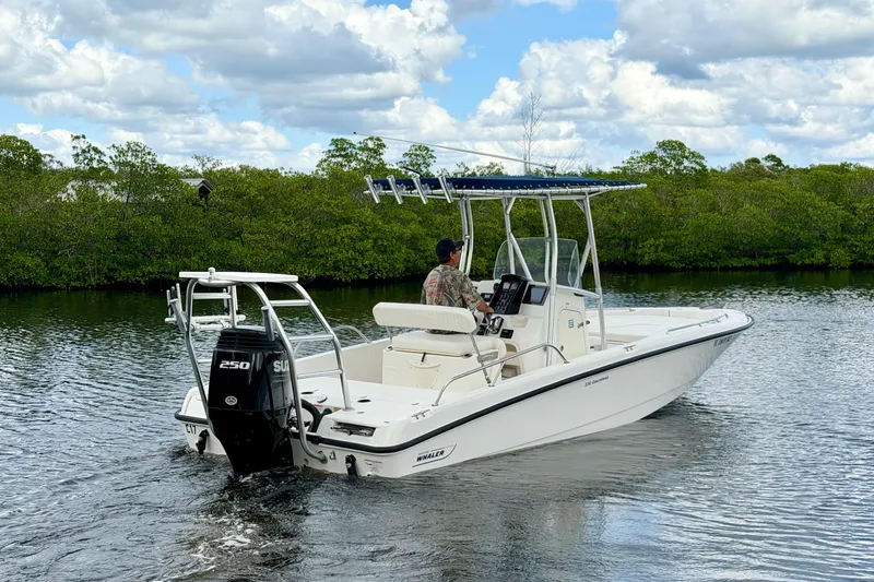 Slide: The Image of 2009 Boston Whaler 230 Dauntless boat cruising on a calm river under a cloudy sky. - 3