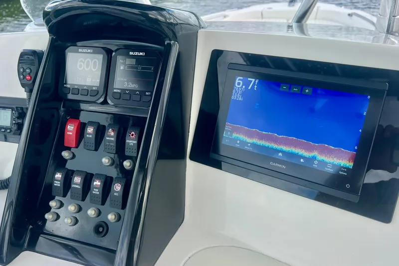 Slide: The Image of 2009 Boston Whaler 230 Dauntless dashboard with Suzuki controls and Garmin display. - 4