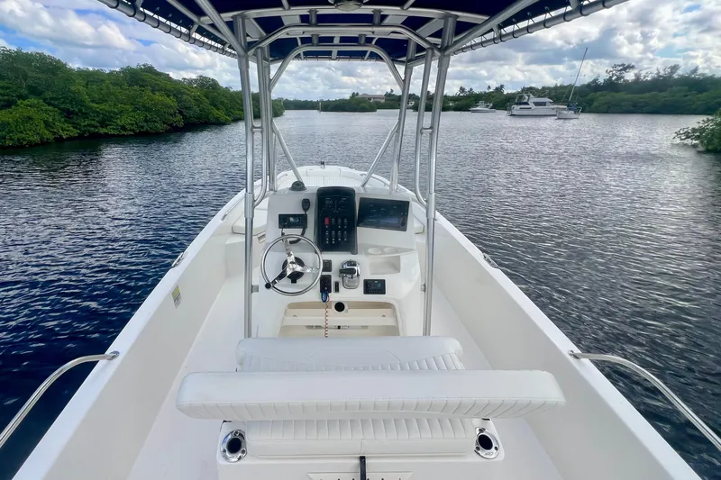 Slide: The Image of 2009 Boston Whaler 230 Dauntless boat on calm water, featuring a sleek console and seating. - 7