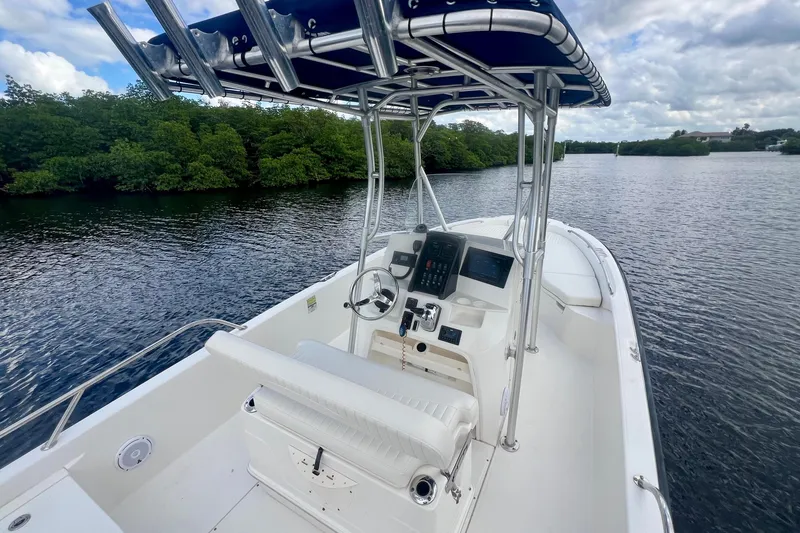 Slide: The Image of 2009 Boston Whaler 230 Dauntless boat on calm water, featuring a sleek console and seating. - 9