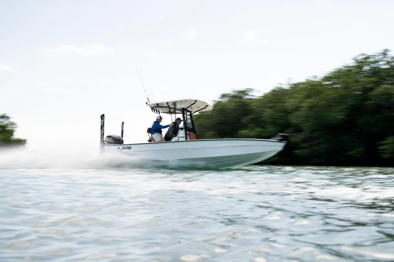 Slide: The Image of 2026 Avid 23 Mag boat speeding on water near lush greenery. - 5