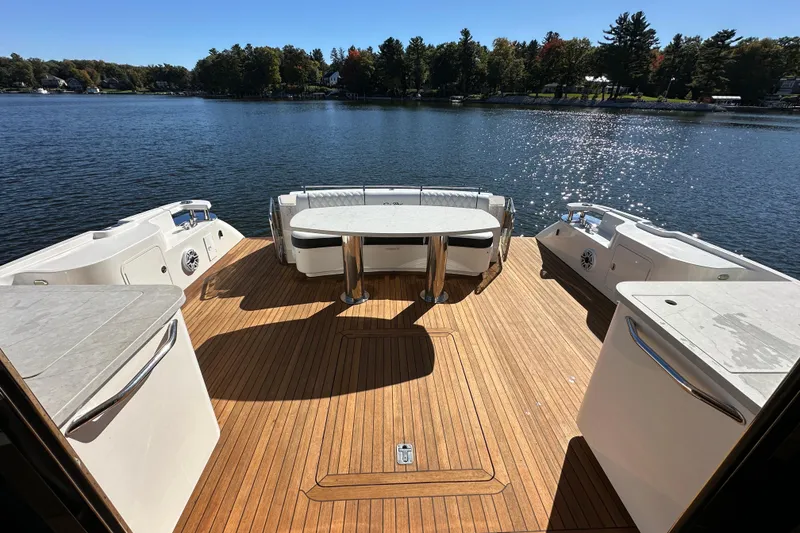 Slide: The Image of 2007 Sea Ray 60 Sundancer yacht deck with seating and table, overlooking serene lake. - 5