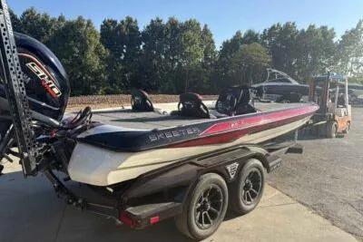 Slide: The Image of 2024 Skeeter FXR21 FLEX boat on trailer, parked outdoors, with trees in background. - 4