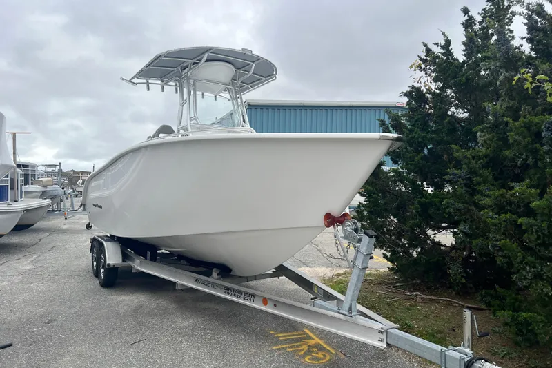 The Image of 2026 Cape Horn 22 OS boat on trailer, parked outdoors near trees and buildings. - 0