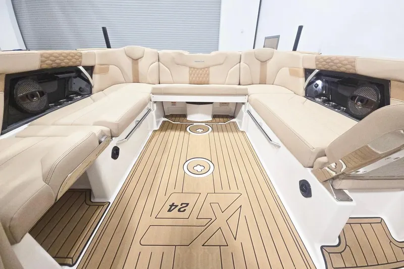 Slide: The Image of 2023 MasterCraft XT24 boat interior with beige seating and wood-style flooring. - 6