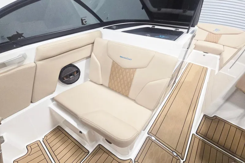 Slide: The Image of 2023 MasterCraft XT24 boat interior with beige seating and wood-style flooring. - 7