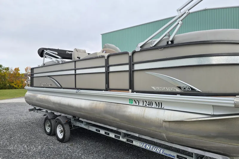 Slide: The Image of 2015 Premier 230 SunSation RF pontoon boat with black canopy, parked near a green building. - 4