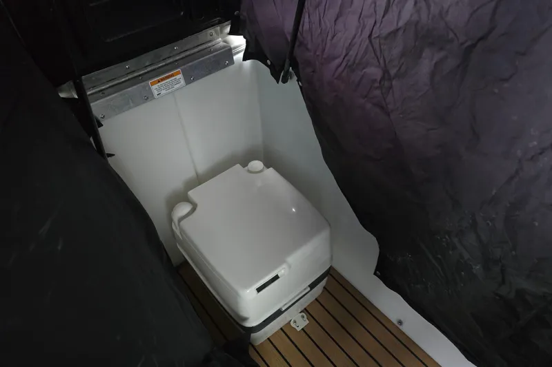 Slide: The Image of Portable toilet inside 2015 Premier 230 SunSation RF boat, with privacy curtain and wooden flooring. - 46