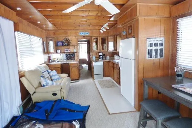 Slide: The Image of 1988 Sumerset 14x65 houseboat interior with wood paneling, kitchen, and seating area. - 3
