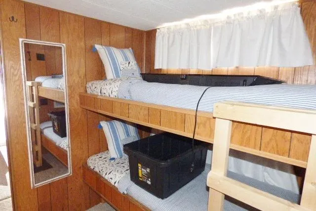 Slide: The Image of 1988 Sumerset 14x65 houseboat interior with wooden bunk beds and striped bedding. - 6