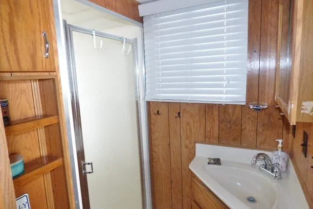 Slide: The Image of 1988 Sumerset 14x65 bathroom with wood paneling, shower, and sink. - 9