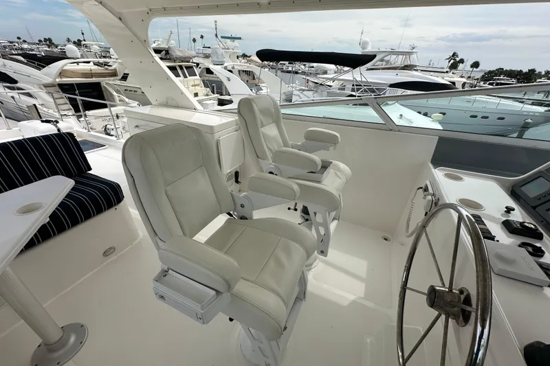 Slide: The Image of 2003 Pacific Mariner 65 SE Motoryacht helm with white captain chairs and steering wheel. - 62