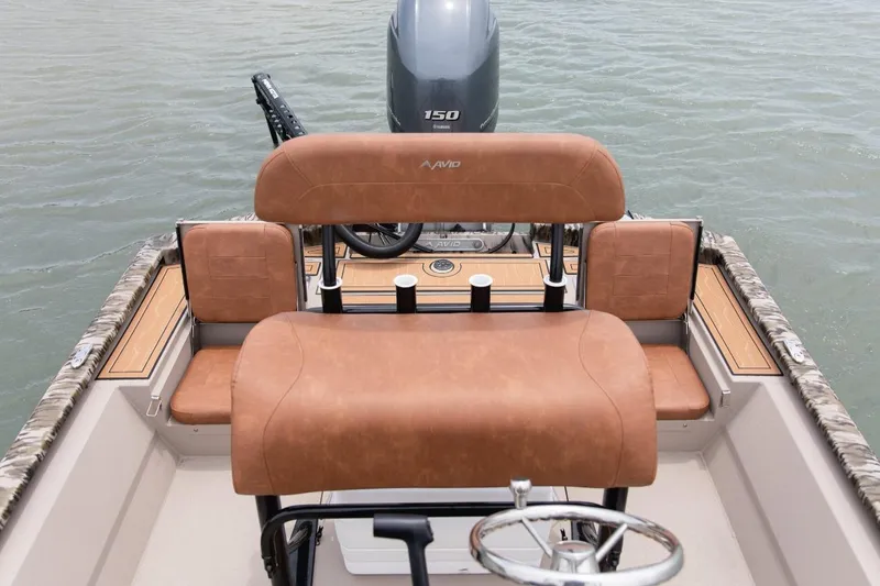 Slide: The Image of 2026 Avid 21 FST boat interior with tan seating and steering wheel on water. - 12