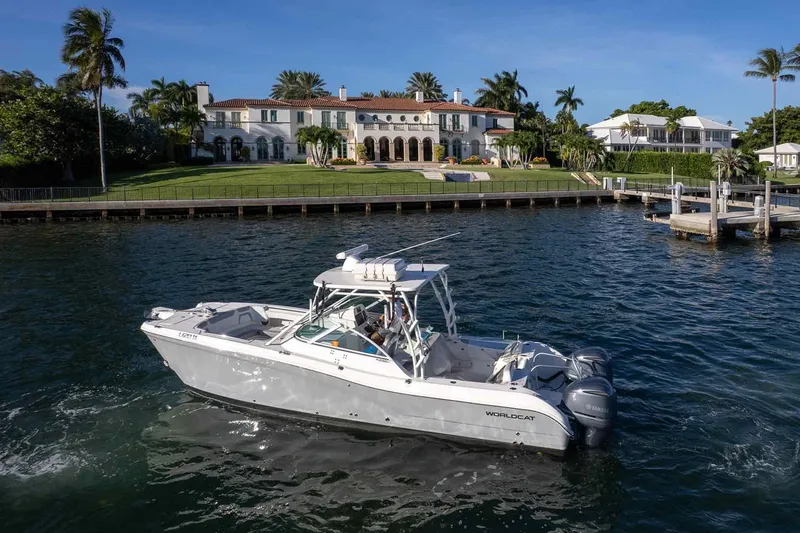 Slide: The Image of 2017 World Cat 295 DC boat cruising near a luxurious waterfront mansion. - 16