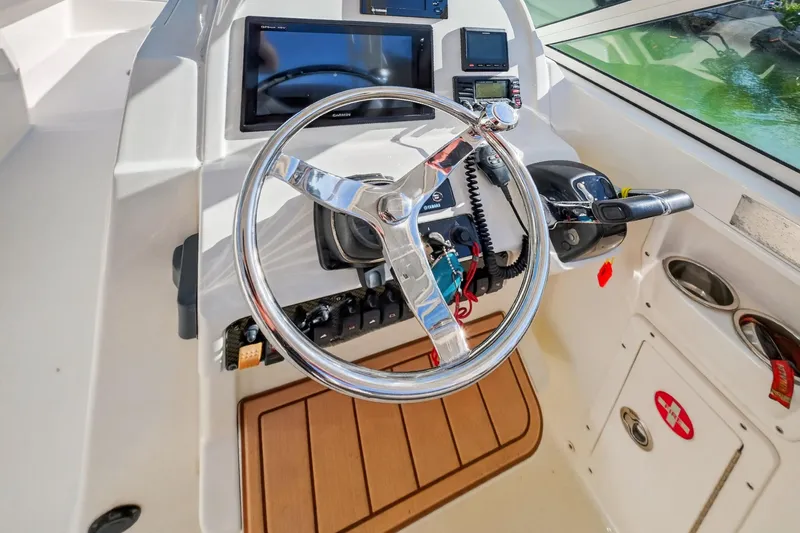 Slide: The Image of 2017 World Cat 295 DC boat helm with steering wheel and navigation controls. - 18