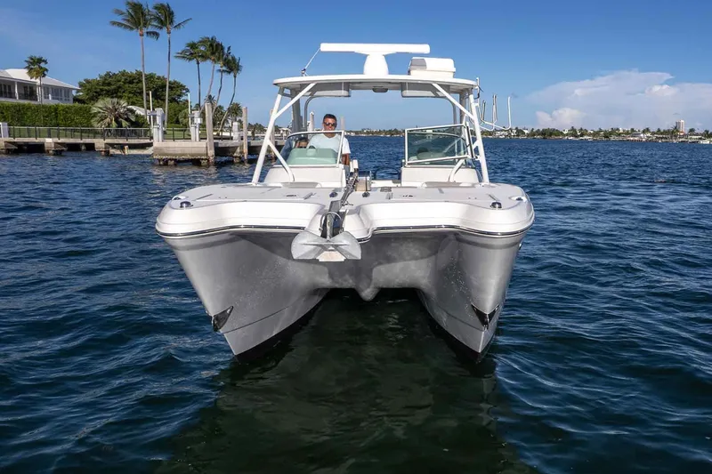 Slide: The Image of 2017 World Cat 295 DC boat on water, with clear blue sky and palm trees. - 35