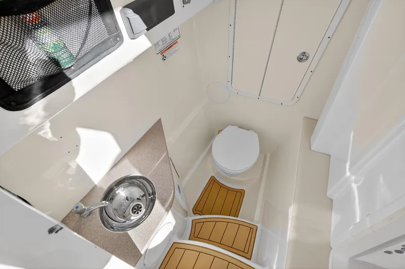 Slide: The Image of 2017 World Cat 295 DC boat interior with compact bathroom, sink, and toilet. - 48