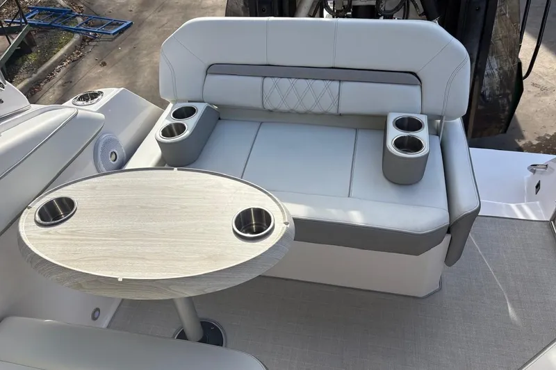 Slide: The Image of 2021 Regal 26 Express boat interior with cushioned seating and table with cup holders. - 16