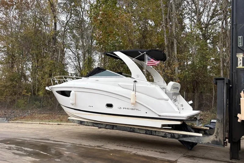 Slide: The Image of 2021 Regal 26 Express boat on trailer, surrounded by autumn trees. - 2