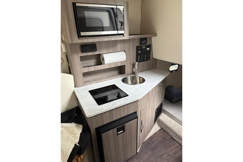 Slide: The Image of 2021 Regal 26 Express boat interior kitchen with microwave, sink, and stove. - 20