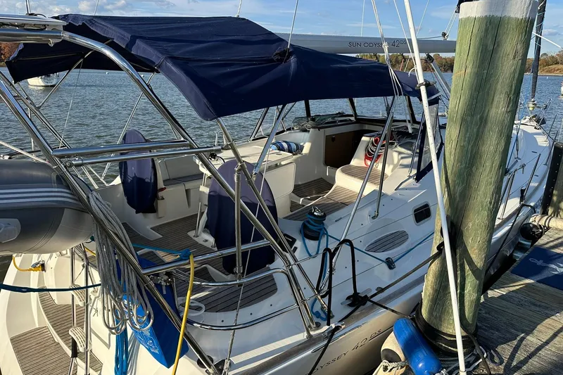 Slide: The Image of 2008 Jeanneau Sun Odyssey 42 DS sailboat docked, featuring a spacious cockpit and blue canopy. - 2