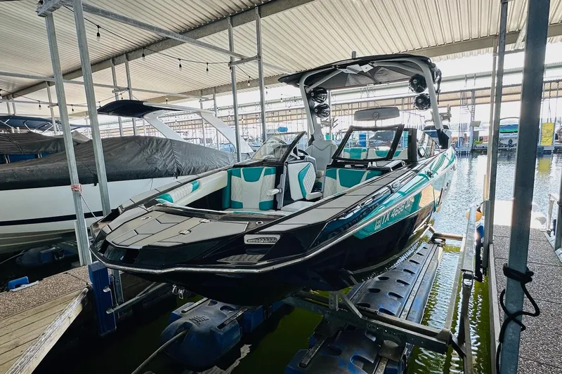 Slide: The Image of 2021 Malibu M240 boat docked in a covered marina, showcasing sleek design and modern features. - 13
