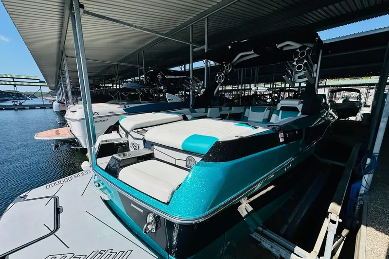 Slide: The Image of 2021 Malibu M240 boat docked, featuring sleek design and vibrant teal color. - 16