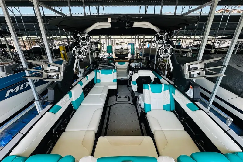 Slide: The Image of 2021 Malibu M240 boat interior with teal and white seating, advanced sound system, and sleek design. - 17