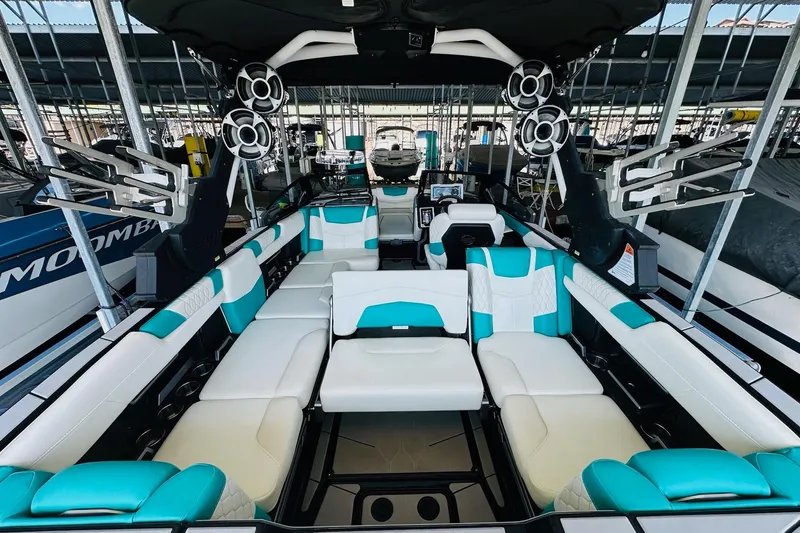 Slide: The Image of 2021 Malibu M240 boat interior with teal and white seating, advanced sound system, and sleek design. - 18