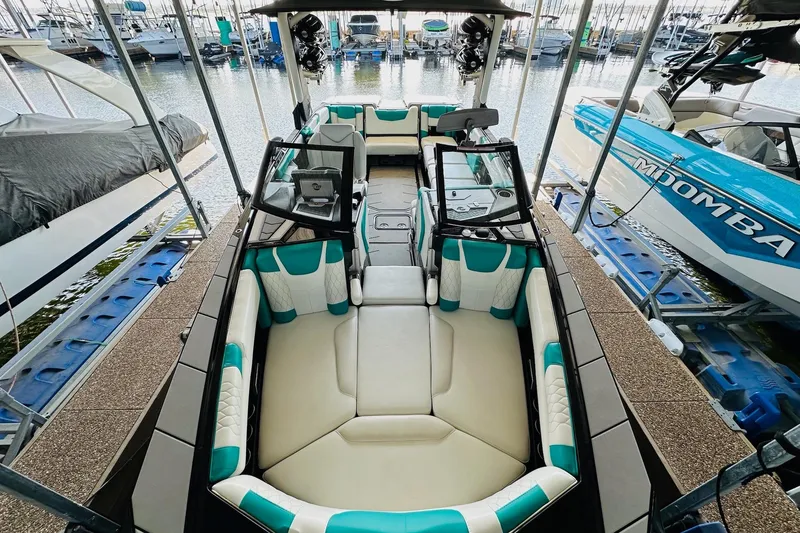 Slide: The Image of 2021 Malibu M240 boat with spacious seating, docked alongside other boats. - 19