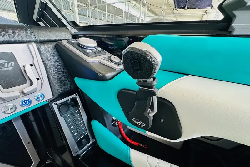 Slide: The Image of Interior of 2021 Malibu M240 boat with modern controls and turquoise accents. - 24