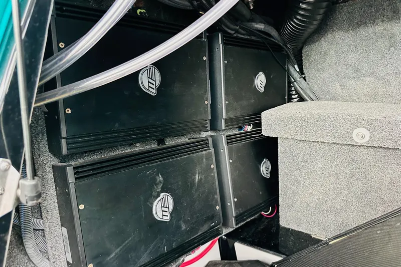 Slide: The Image of 2021 Malibu M240 audio system amplifiers in a carpeted compartment. - 35