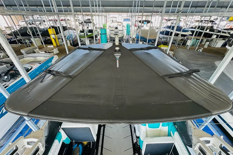 Slide: The Image of 2021 Malibu M240 boat with black cover in a marina storage area. - 37