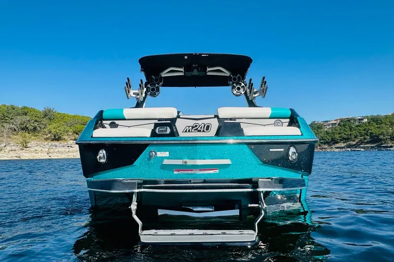 Slide: The Image of 2021 Malibu M240 boat on water, rear view, vibrant blue, clear sky background. - 4