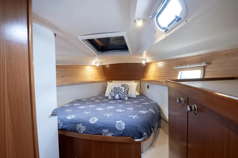 Slide: The Image of 2024 Catalina 445 yacht cabin with cozy bed, wooden interior, and natural light. - 9