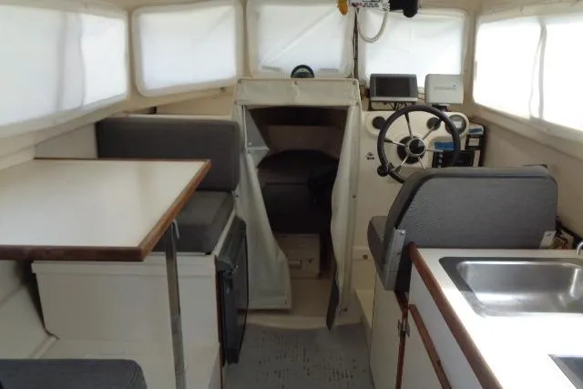 Slide: The Image of 2004 C-Dory 22 Cruiser interior with steering wheel, seating, table, and sink. - 22