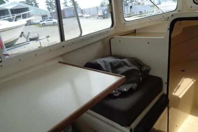 Slide: The Image of Interior of 2004 C-Dory 22 Cruiser with seating and table, docked outdoors. - 40